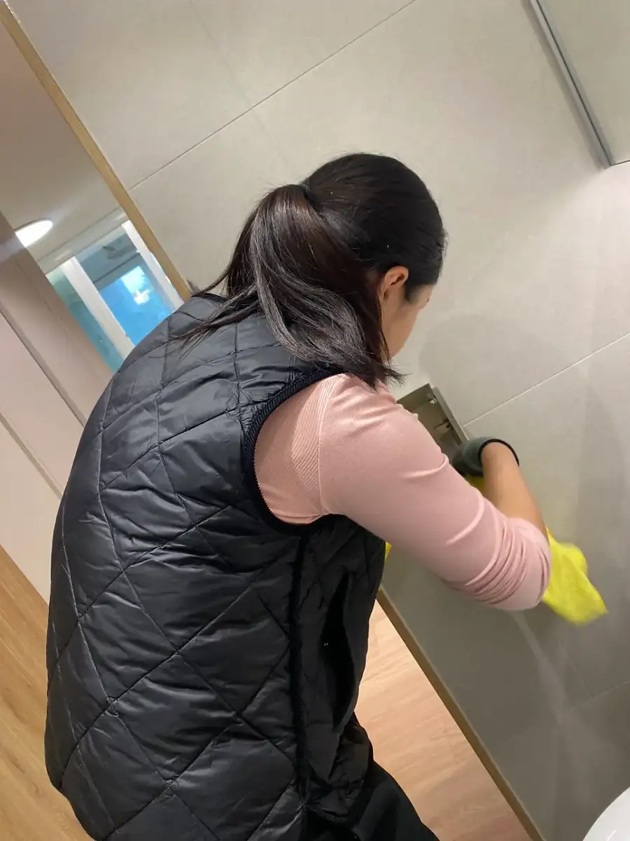 장갑을 끼고 벽 모서리를 한 곳씩 확인하며 닦는 작업자